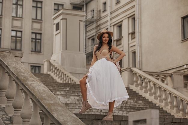 bella joven caminando por la ciudad con falda blanca y sombrero