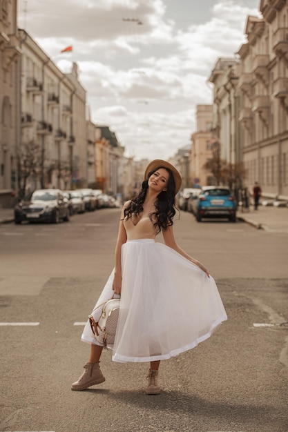 bella joven caminando por la ciudad con falda blanca y sombrero