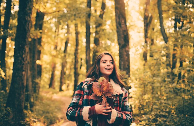 Foto bella joven feliz con una hoja amarilla brillante en el parque clima cálido soleado hermoso