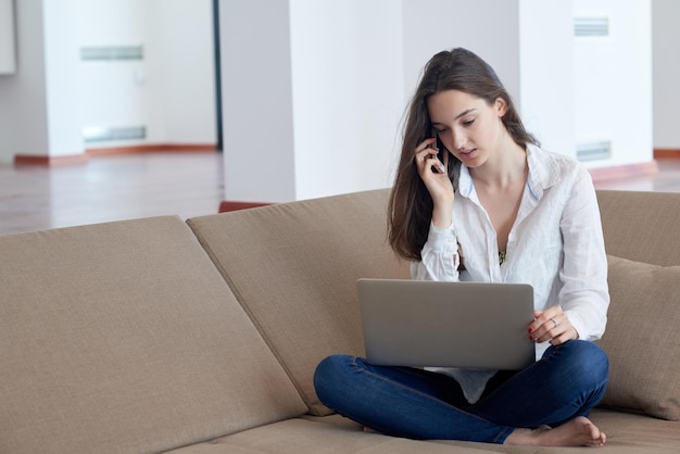 bella joven se relaja y trabaja en una computadora portátil moderna oficina en casa mientras escucha música con auriculares blancos