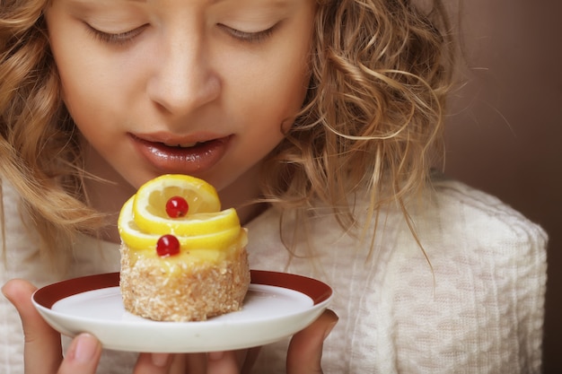 La bella joven sonriente con un pastel