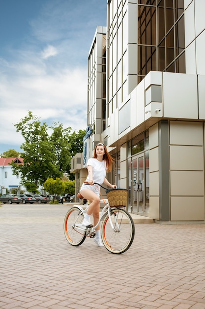 Una bella joven viaja a la ciudad en bicicleta. Alquilar y contratar transporte para el día. Niña feliz monta una bicicleta. Estilo de vida deportivo Verano, primavera