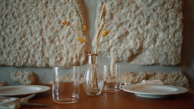 Bella mesa de café con ramos de flores secas en un jarrón de diseño cercano