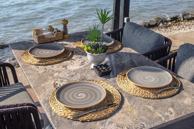 Bella mesa servida de un café moderno junto al mar con platos y flores