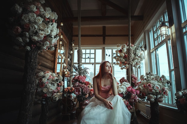 Bella modelo está posando con flores y maquillaje creativo