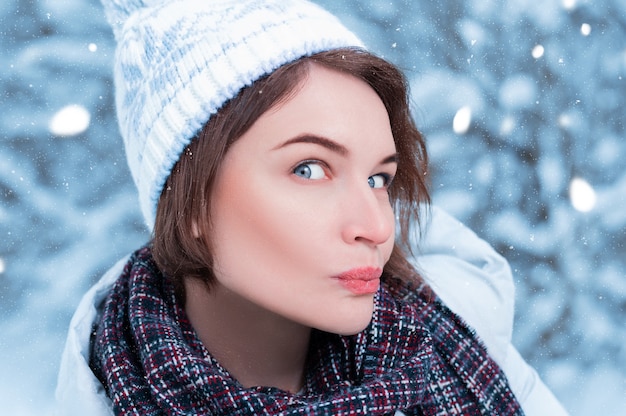 Bella modelo hace una cara de sorpresa divertida. Bosque de invierno. Ropa de abrigo y concepto de compras navideñas. Técnica mixta