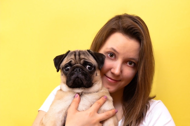 Bella mujer abrazando a su perro pug