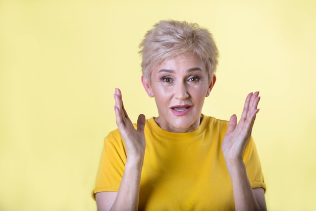 Bella mujer adulta en camiseta sobre fondo amarillo