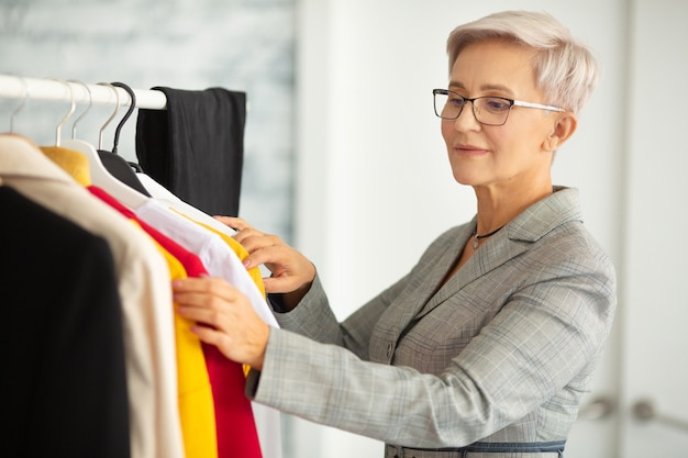 Bella mujer adulta en traje elige ropa