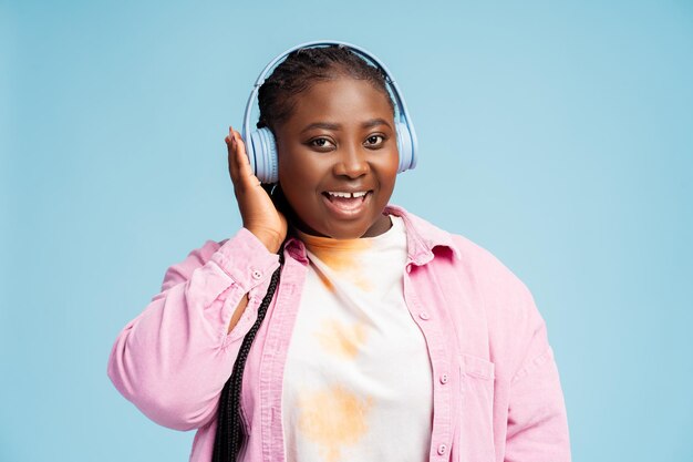 Bella mujer afroamericana con auriculares inalámbricos escuchando música mirando a la cámara