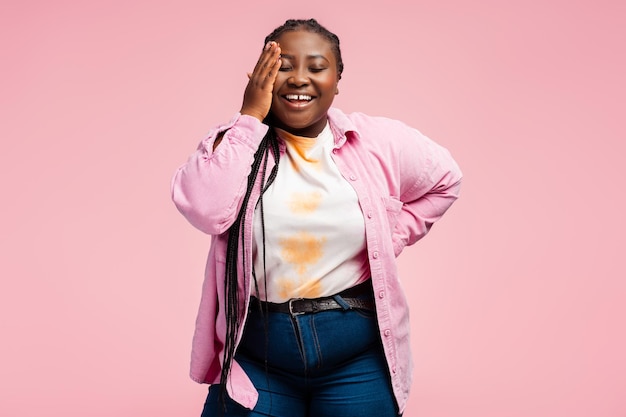 Bella mujer afroamericana emocionada con trenzas elegantes con una camisa rosa de moda y un atuendo casual