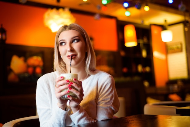 Bella mujer bebiendo un capuchino en un café