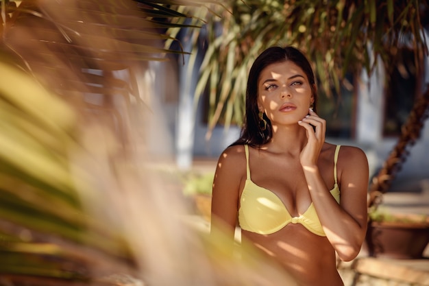 Foto bella mujer en bikini se encuentra entre plantas tropicales