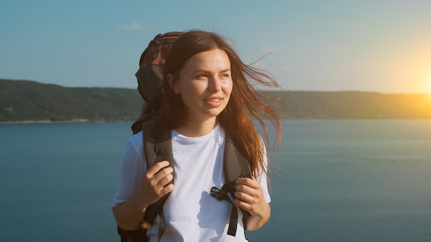 La bella mujer caminando con mochila por la costa