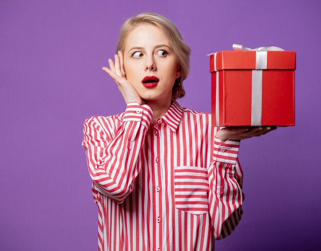 Bella mujer en camisa de rayas rojas con caja de regalo