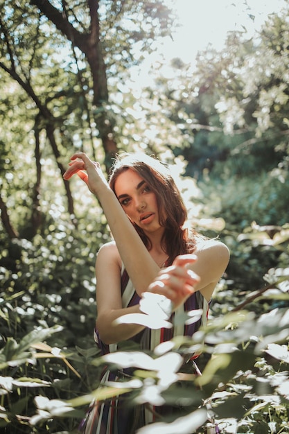 Foto bella mujer caucásica levantando las manos al nivel de su cabeza en el bosque