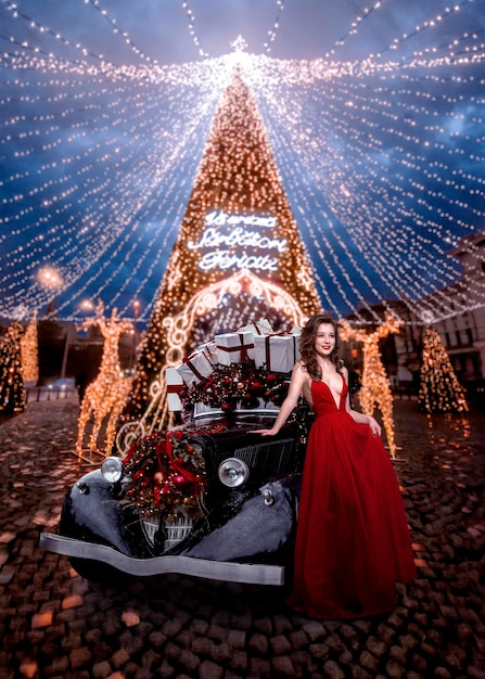 Bella mujer con un coche decorado con regalos de Navidad