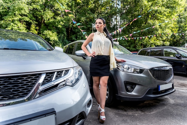 Bella mujer entre coches en el lugar de estacionamiento