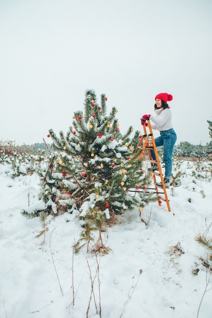 Bella mujer decorar el árbol de navidad al aire libre