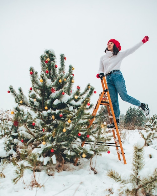 Bella mujer decorar el árbol de navidad al aire libre