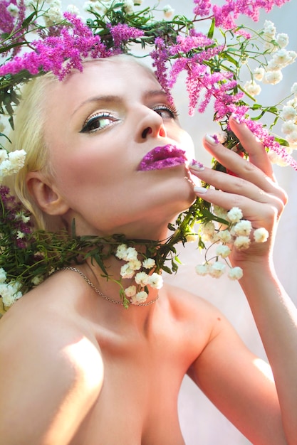 Bella mujer con diseño de flor rosa de verano Astilbe en los labios y en los dedos