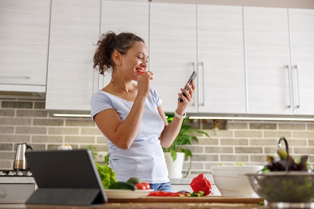 Bella mujer está cocinando deliciosos platos en la cocina de su casa