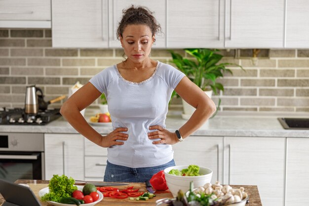 Bella mujer está cocinando deliciosos platos en la cocina de su casa