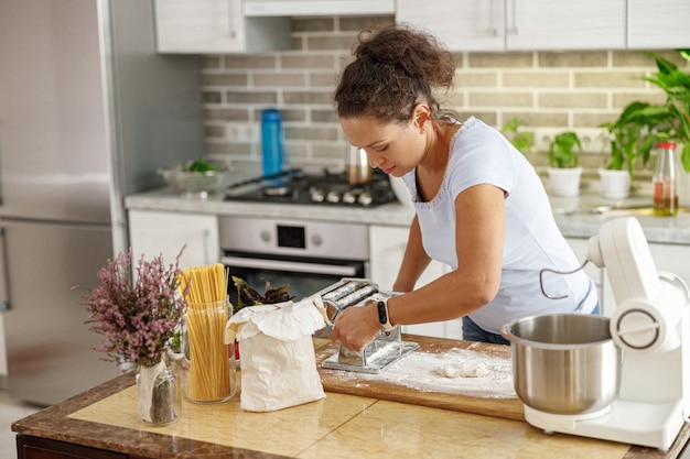 Bella mujer está cocinando deliciosos platos en la cocina de su casa