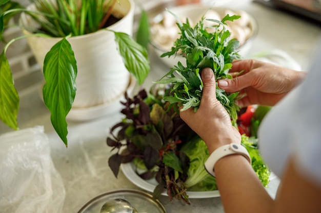 Bella mujer está cocinando deliciosos platos en la cocina de su casa