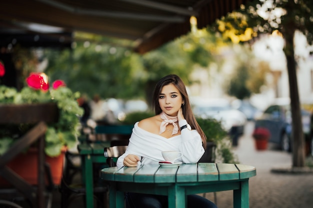 Bella mujer está sentada en una cafetería.