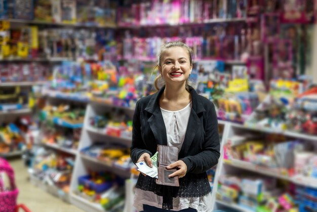 Bella mujer con euro posando en la tienda de juguetes