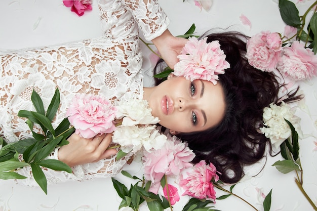 Bella mujer con flores de peonía rosa