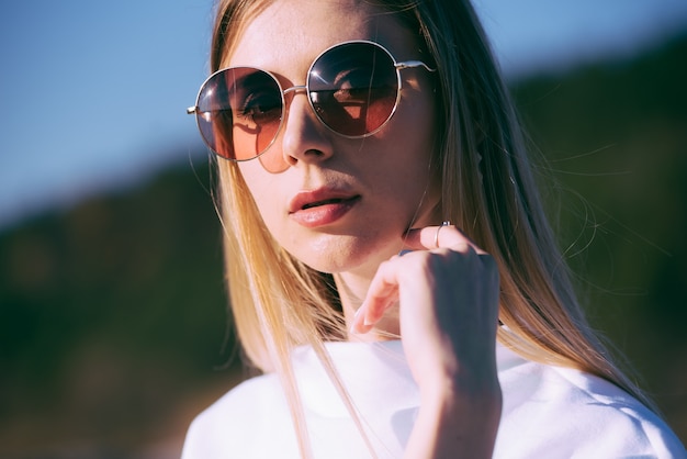 Bella mujer con gafas de sol y ropa blanca