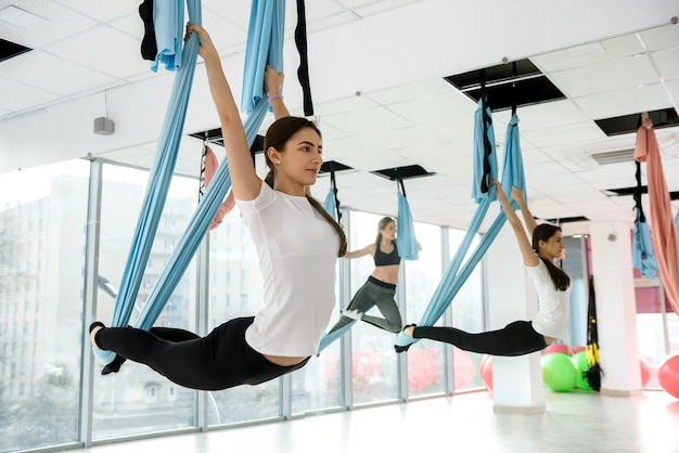 Bella mujer haciendo ejercicios de yoga aéreos en clase