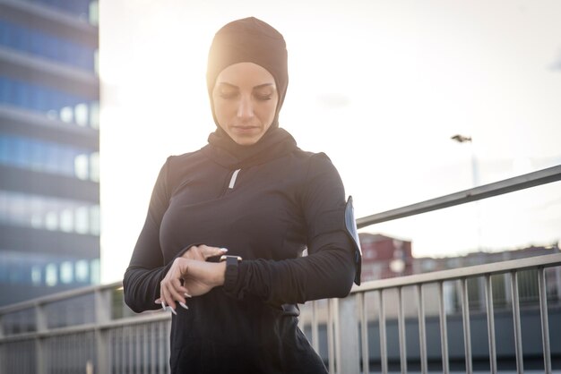 Foto bella mujer con hijab de pie contra el edificio durante el amanecer