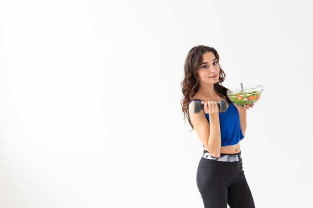 Foto bella mujer joven bebiendo agua contra un fondo blanco