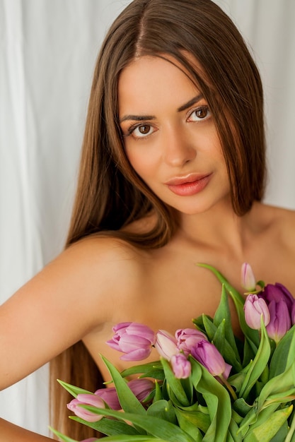 Foto bella mujer joven de cabello largo sostiene un ramo de tulipanes retrato de mujer sobre fondo blanco