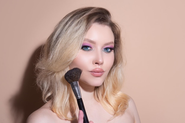 Bella mujer joven con maquillaje rubor pincel tratamiento facial cosmetología belleza y spa retrato