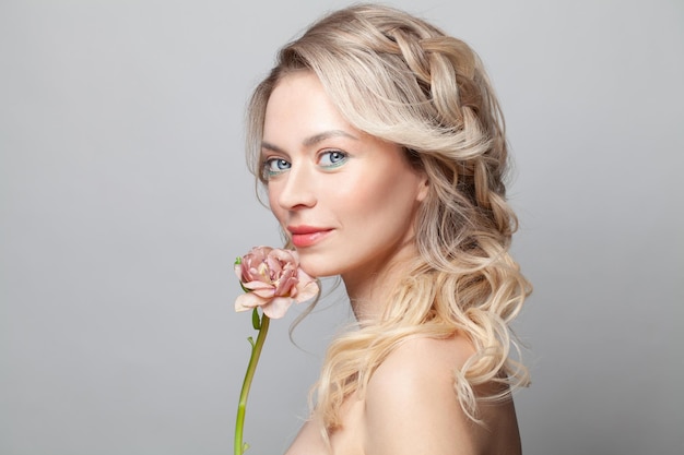 Foto bella mujer joven con piel limpia y fresca toca su cara flor tratamiento facial cosmetología belleza y spa