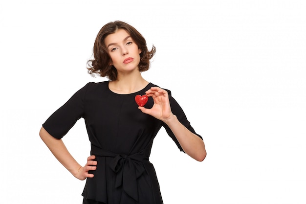 Una bella mujer morena con un vestido negro tiene un corazón rojo decorativo en sus manos