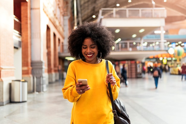 Bella mujer con móvil en la estación de tren. Concepto de comunicación.