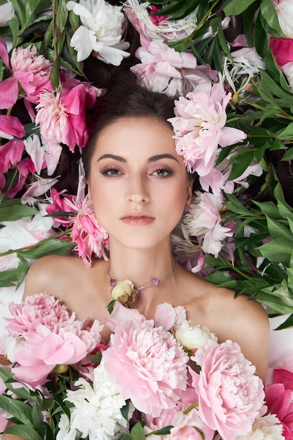 Bella mujer con muchas flores rosas