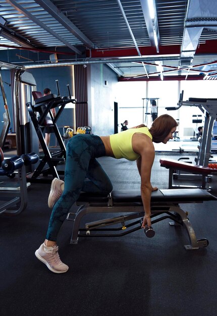 Bella mujer musculosa haciendo ejercicio con pesas en el gimnasio concepto de culturismo
