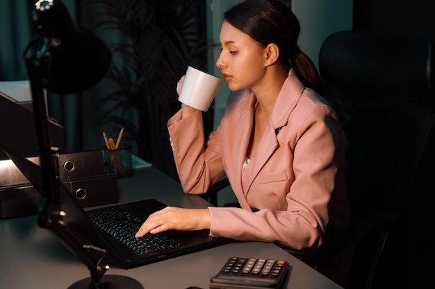 Bella mujer de negocios sentada con traje rosado bebiendo postulado de café