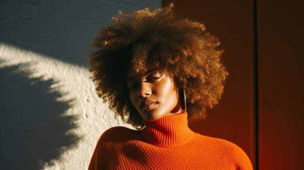 Foto bella mujer negra con cabello afro de pie cerca de la pared en la luz directa del sol brillante