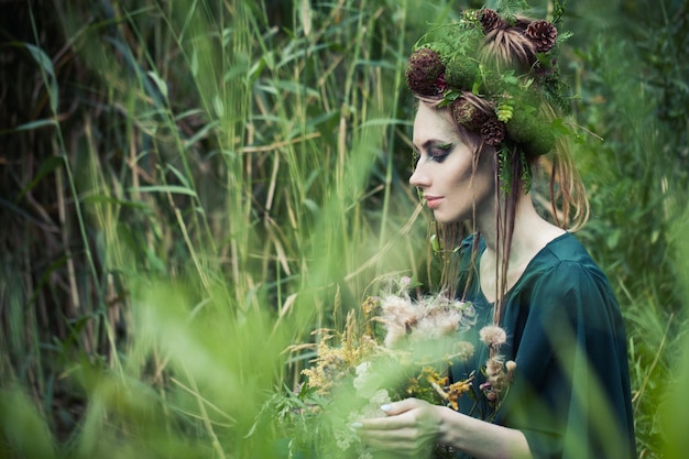 Bella mujer ninfa de la tierra en el fondo de hierba verde al aire libre