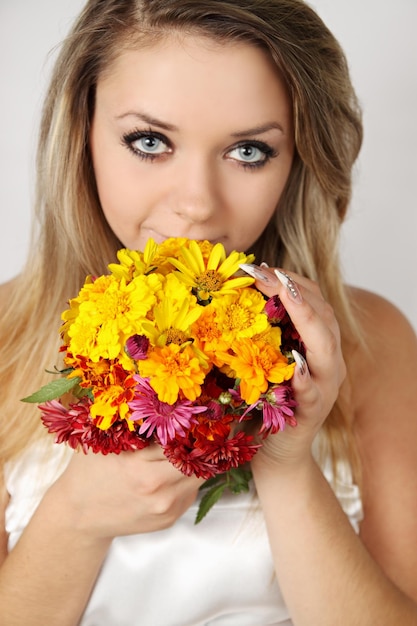 Bella mujer oliendo un ramo de flores de otoño