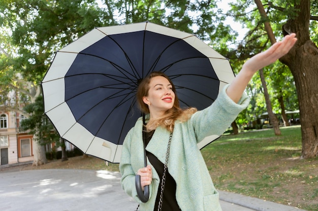 Bella mujer con paraguas buscando lluvia