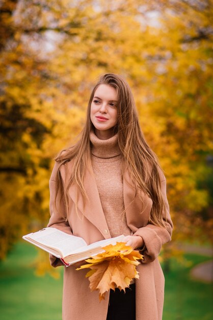 Bella mujer pasar tiempo en un parque durante la temporada de otoño