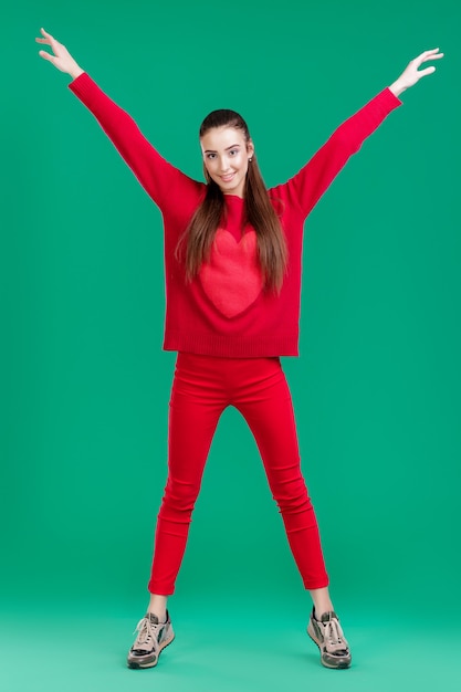 Bella mujer con pelo largo en suéter rojo sobre fondo verde